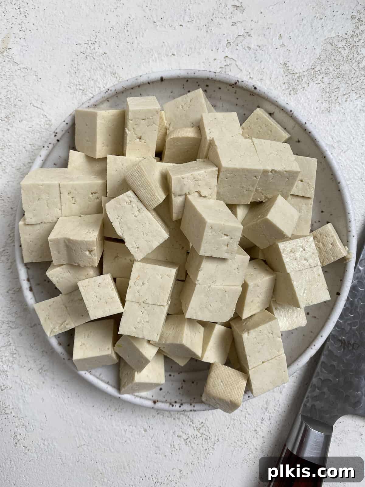 Zesty Plant-Based Hot and Sour Soup 8 cubed tofu in a white plate against a white background
