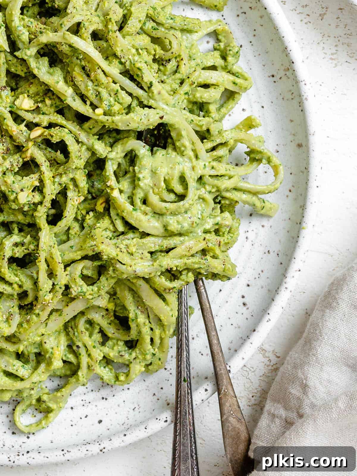 Lush Avocado Pesto Pasta 2 Vibrant green avocado pesto pasta plated on a light surface, ready to be enjoyed.