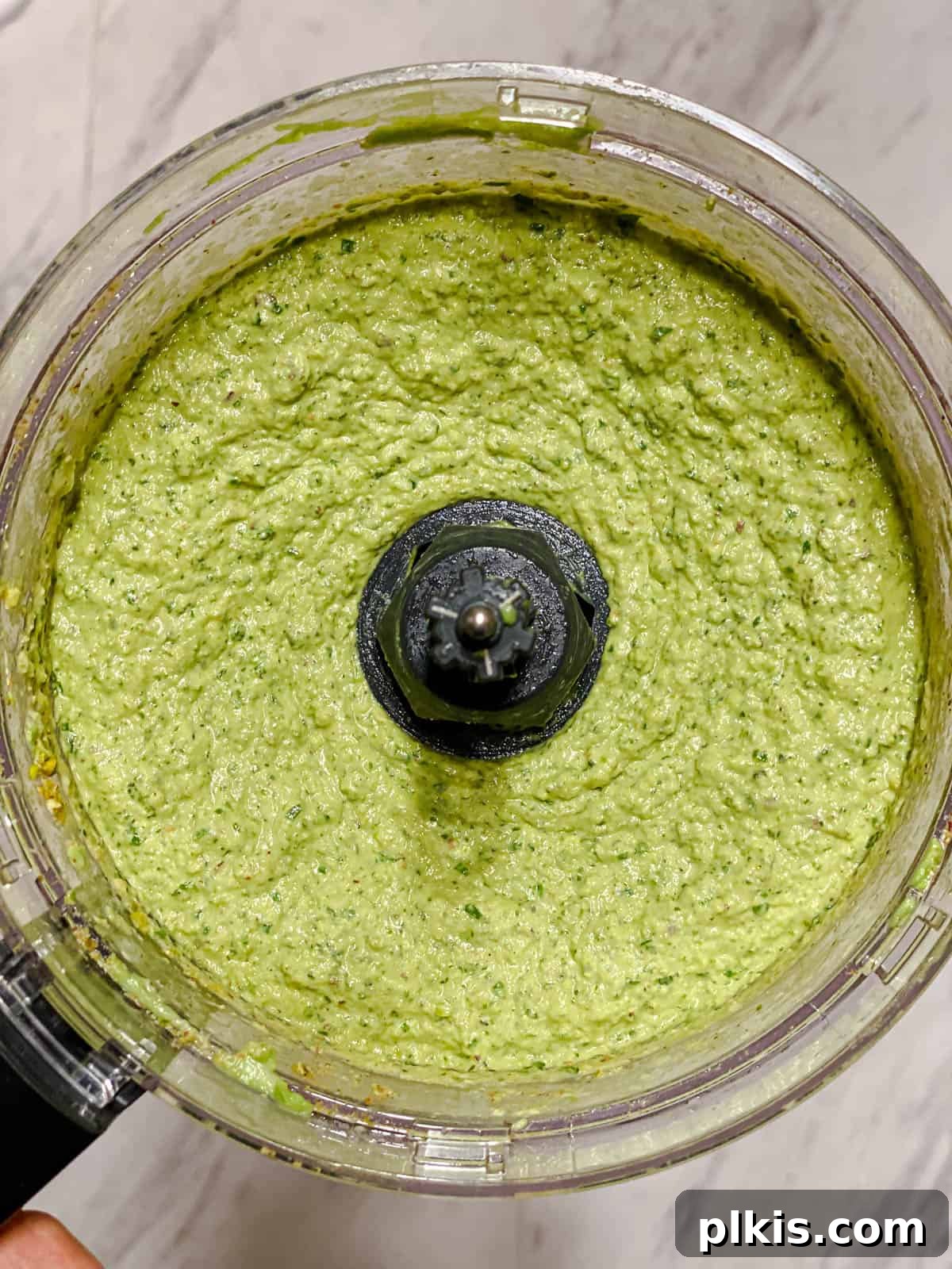 Lush Avocado Pesto Pasta 6 Freshly blended avocado pesto in a food processor bowl, showcasing its creamy texture and vibrant green color.