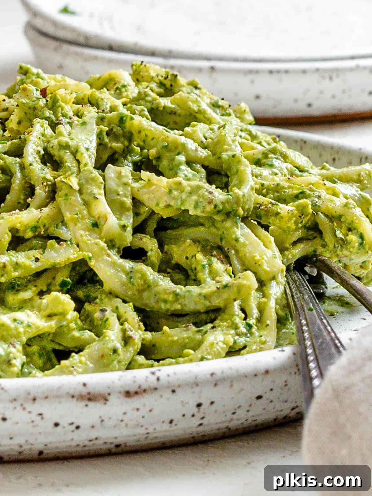 Lush Avocado Pesto Pasta 8 A close-up of a serving of amazing avocado pesto pasta, highlighting the creamy sauce and fresh basil garnish.