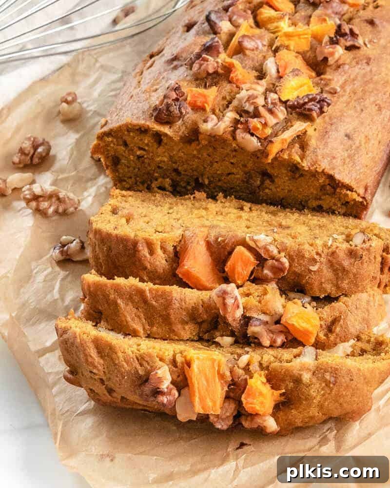 Cooked Vegan Pumpkin Bread sliced on parchment paper, showcasing its moist texture and golden-brown crust.