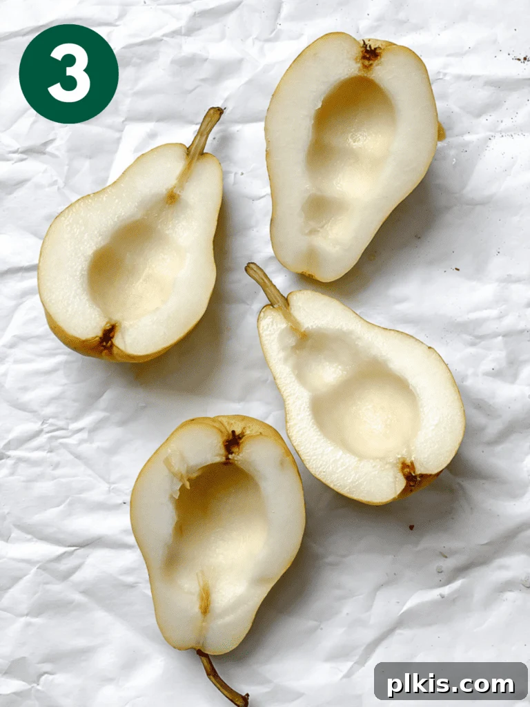 Sweet Baked Pears with Nutty Fruit Filling 6 Fresh pears, sliced in half and cored, laid out on a white surface, demonstrating the preparation stage for stuffing.