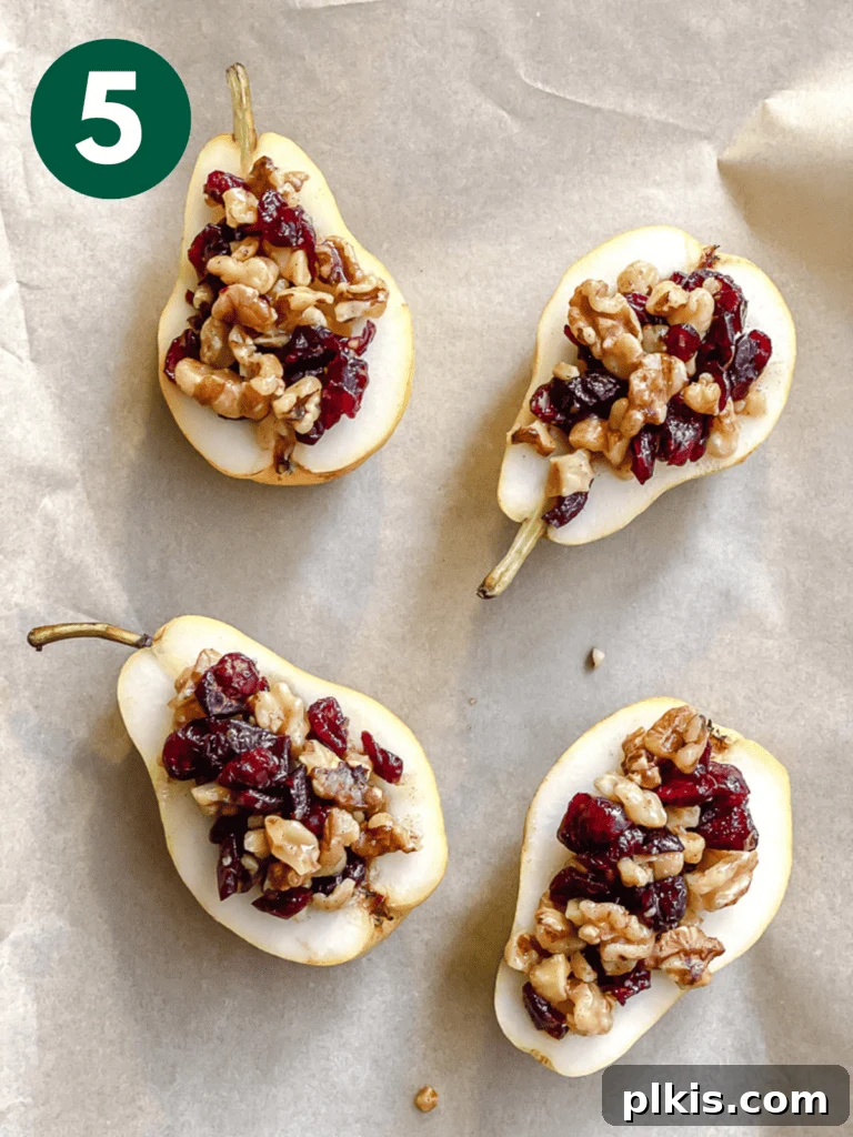 Sweet Baked Pears with Nutty Fruit Filling 8 Stuffed pear halves arranged neatly on parchment paper on a baking sheet, ready for the oven.