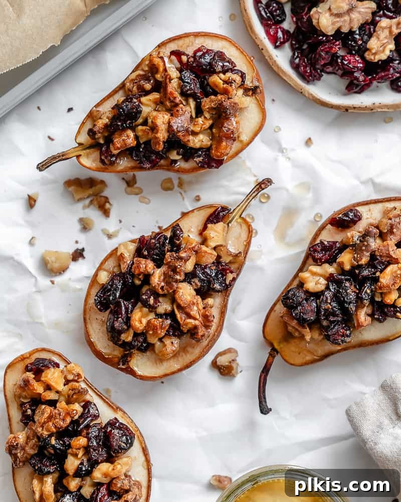 Sweet Baked Pears with Nutty Fruit Filling 10 Two perfectly baked pears, generously stuffed with a golden-brown nut and dried fruit mixture, presented on a white surface, ready to be enjoyed as a gourmet dessert.