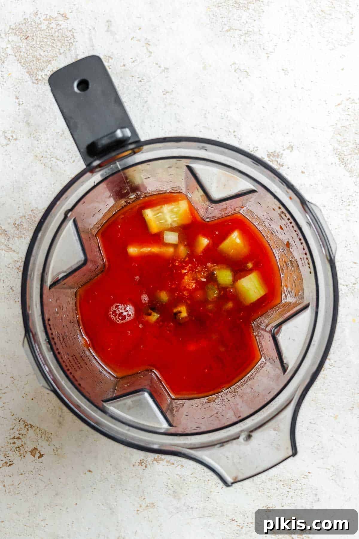 Alkolsüz Bloody Mary Tarifi 4 Process shot showing raw ingredients like tomato juice, cucumber, celery, and spices added to a blender.