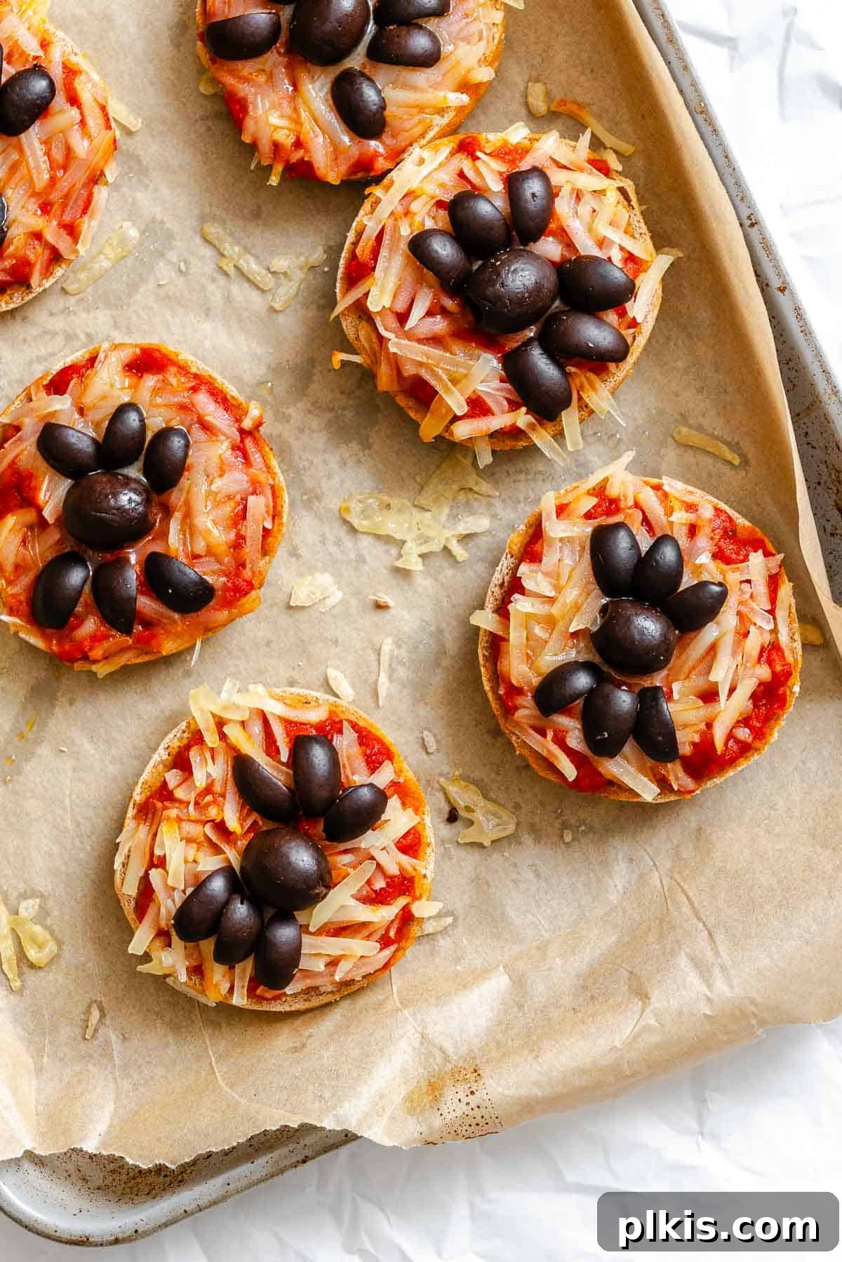 Spooky Spider Pizza Bites 7 Process shot showing freshly baked Mini Spider Pizza Bagel Bites on a baking tray, with melted cheese and crispy edges.