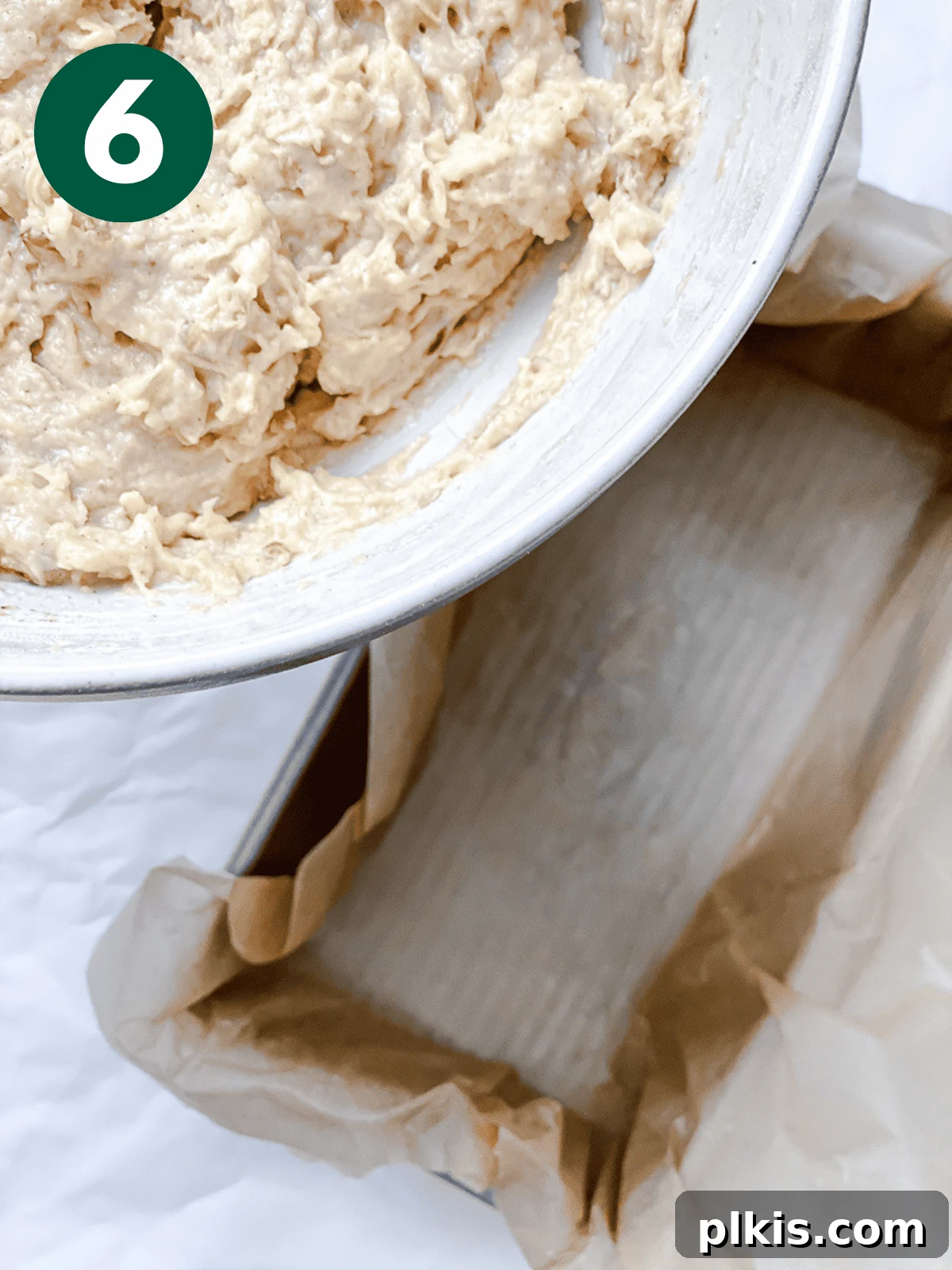 Spiced Apple Bread 9 Thick apple cinnamon bread batter being carefully poured from a large bowl into a parchment-lined loaf pan.