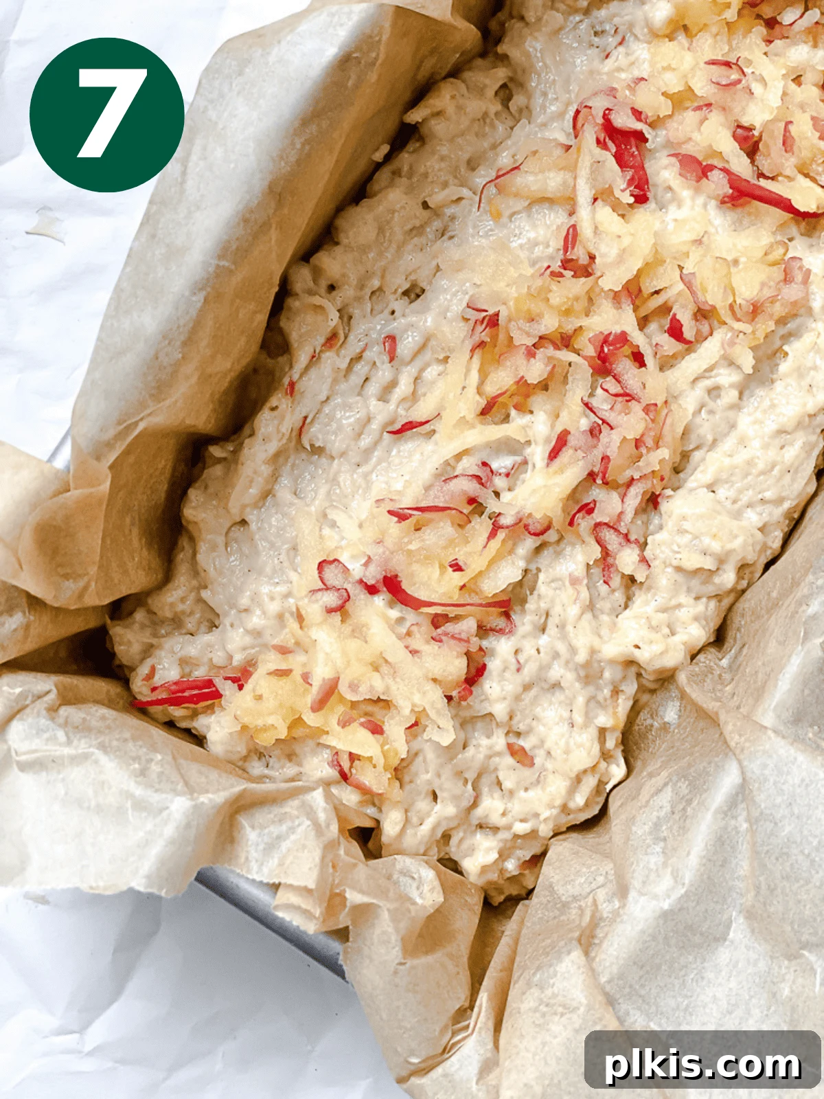 Spiced Apple Bread 10 Unbaked apple cinnamon bread batter smoothed out in a loaf pan, with a scattering of shredded apples on top, ready for the oven.