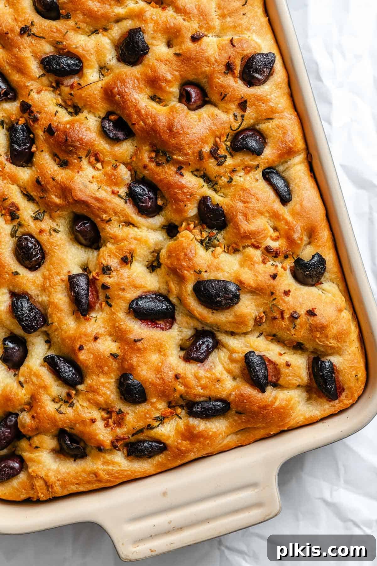 Aromatic Garlic Herb Vegan Focaccia 2 Completed Vegan Focaccia (Garlic and Herb) in baking dish, garnished with olives and herbs.