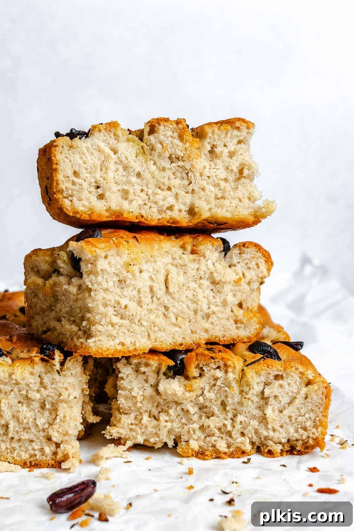 Aromatic Garlic Herb Vegan Focaccia 10 Completed Vegan Focaccia (Garlic and Herb) stacked on each other on a white surface.