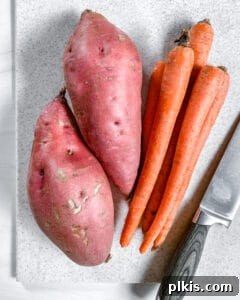 Washed red yams and carrots resting on a white surface, ready for dicing