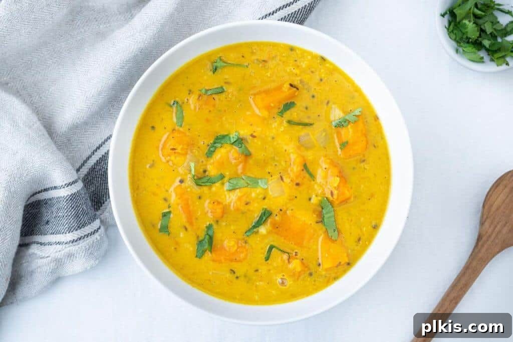 Lentil Mastery 4 A bowl of creamy curried butternut squash lentil soup, garnished with fresh herbs, against a clean white background.