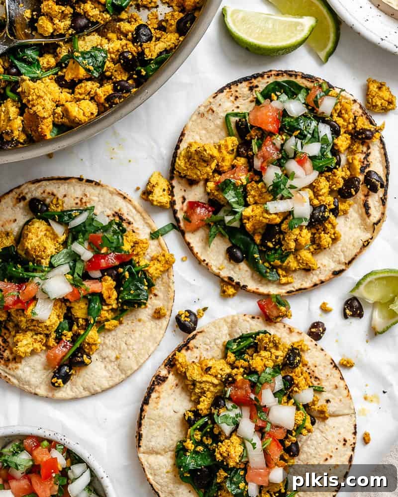 Plant-Powered Morning Tacos 9 Completed Vegan Breakfast Tacos on a white surface alongside pan of filling.