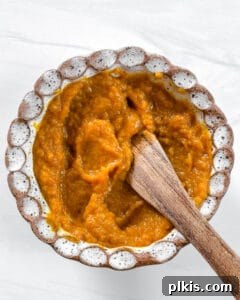 Spiced Pumpkin Date Delights 12 A wooden spoon stirring the pumpkin mixture in a white bowl, showing a smooth and well-combined texture.