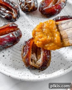 Process shot of pumpkin mixture being spooned into the open center of a sliced date on a white plate.