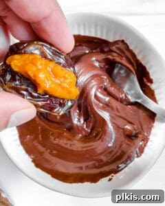 Process shot of a stuffed date being dipped into a bowl of melted chocolate.