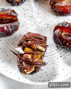 Spiced Pumpkin Date Delights 16 A single stuffed date with a perfect chocolate coating on top, placed on a white plate.