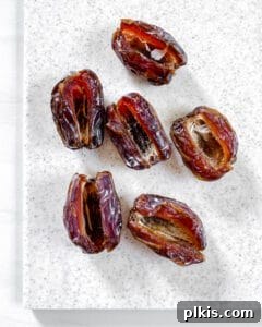 Spiced Pumpkin Date Delights 8 Six Medjool dates, all partially sliced open and ready for stuffing, laid out on a white cutting board.