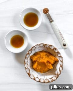 Small bowls containing the individual ingredients for the pumpkin filling, including pumpkin puree, spices, and liquid sweeteners, arranged on a white background.