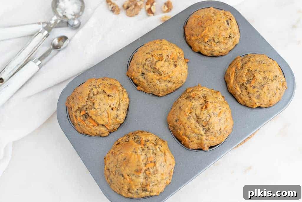 Orange Gold: The Ultimate Carrot Compendium 5 finished carrot muffins in a muffin tin against a white background