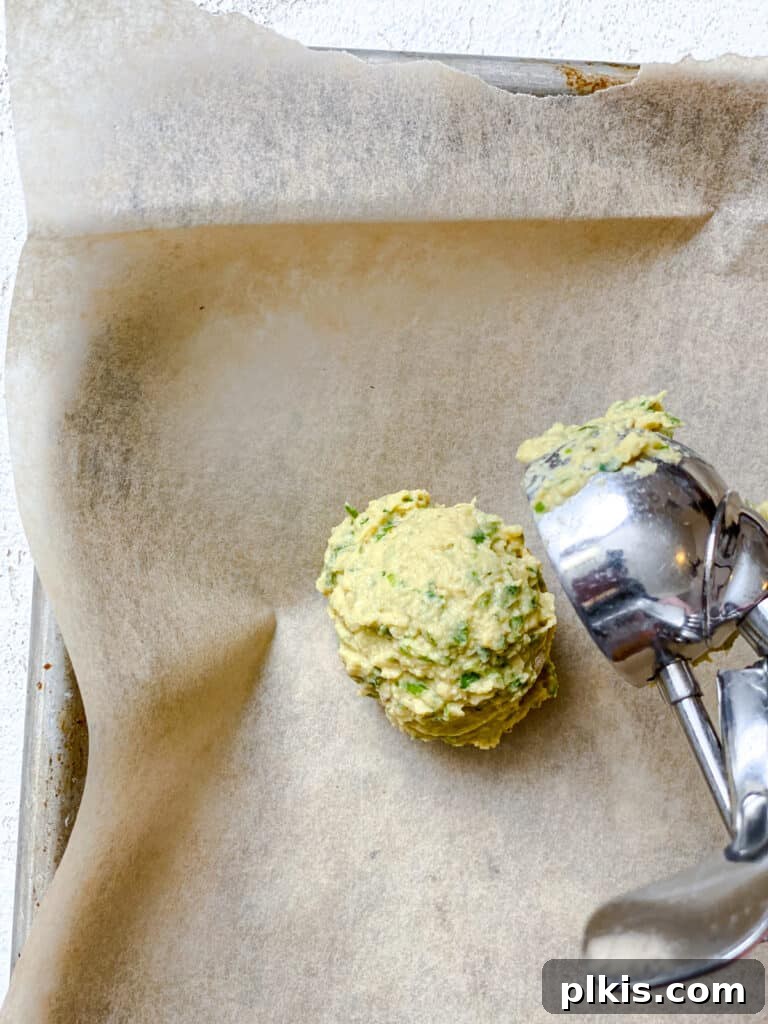 Crispy Healthy Falafel Baked or Air Fried 6 process shot of adding a scoop of baked falafel to baking sheet