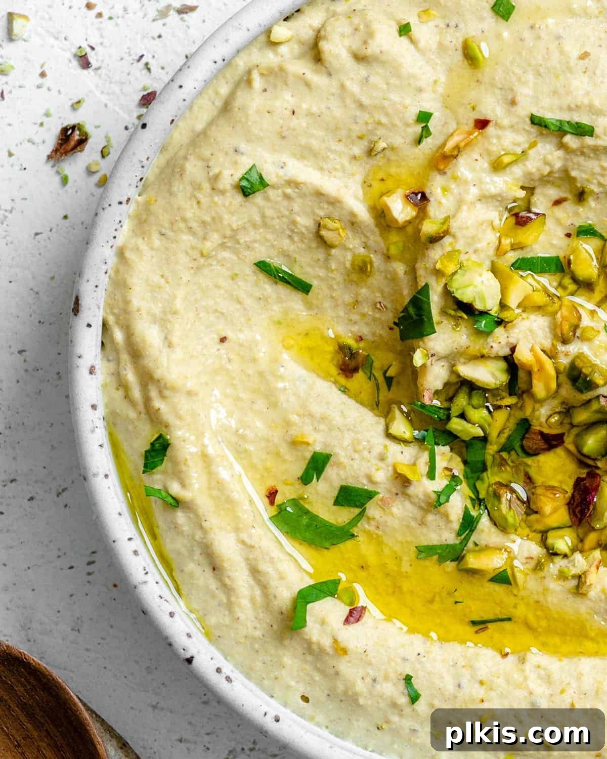 Emerald Pistachio Hummus 6 A beautifully presented bowl of creamy Pistachio Hummus, garnished with fresh herbs and crushed pistachios, ready to be enjoyed.