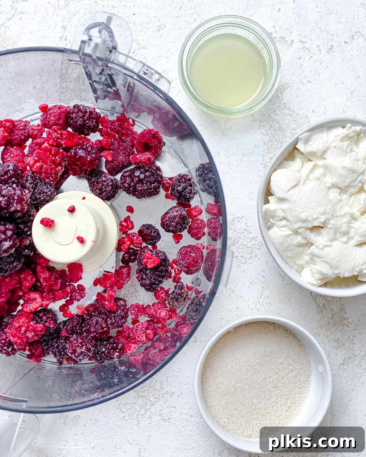 Instant Berry Tofu Nice Cream 4 Step-by-step process image showing all ingredients for the ice cream added to a food processor bowl.