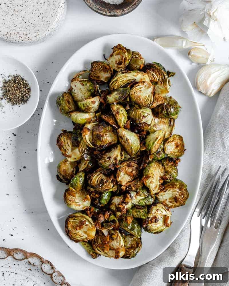 Crispy Air Fryer Brussels Sprouts 2 finished Crispy Air Fryer Brussels Sprouts plated on a white dish against a white background