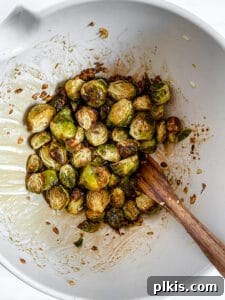 Crispy Air Fryer Brussels Sprouts 14 Air Fryer Brussels Sprouts in white bowl mixed with wet ingredients