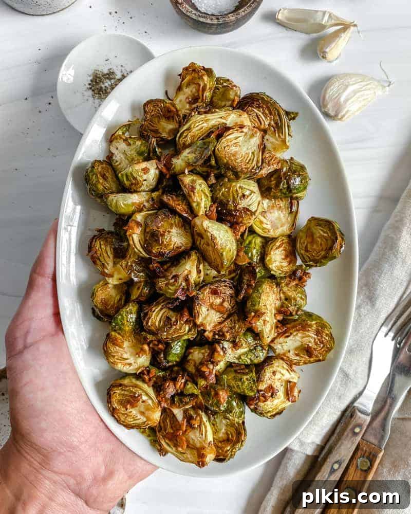 Crispy Air Fryer Brussels Sprouts 15 finished Crispy Air Fryer Brussels Sprouts plated on a white dish against a white background