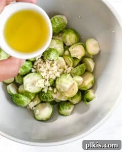 Crispy Air Fryer Brussels Sprouts 8 brussels sprouts in a white bowl with dressing about to be poured into the bowl