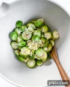 Crispy Air Fryer Brussels Sprouts 9 brussels sprouts in a white bowl with a wooden spoon
