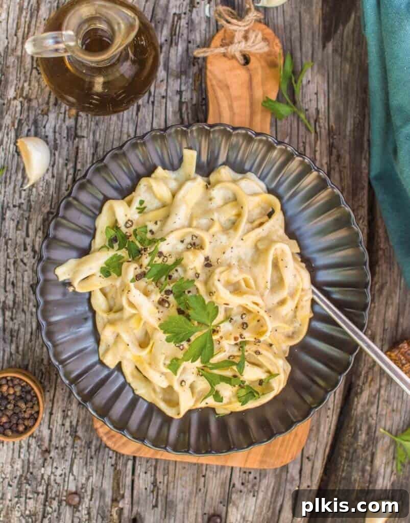 20 Effortless Plant-Based Pasta Dishes for Delicious Dinners 14 finished Vegan Fettuccini Alfredo plated on a dark plate against a dark wooden background