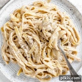 completed Fettuccine Alfredo on a white plate against a white background
