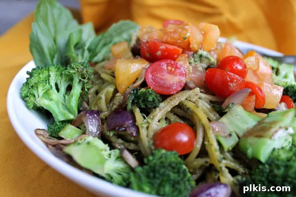 20 Effortless Plant-Based Pasta Dishes for Delicious Dinners 20 finished sunflower seed pesto in a white plate mixed iwth veggies against a dark background