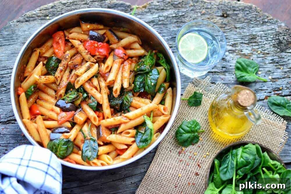 20 Effortless Plant-Based Pasta Dishes for Delicious Dinners 28 finished Eggplant Penne in a dish with ingredients spread out against a dark background