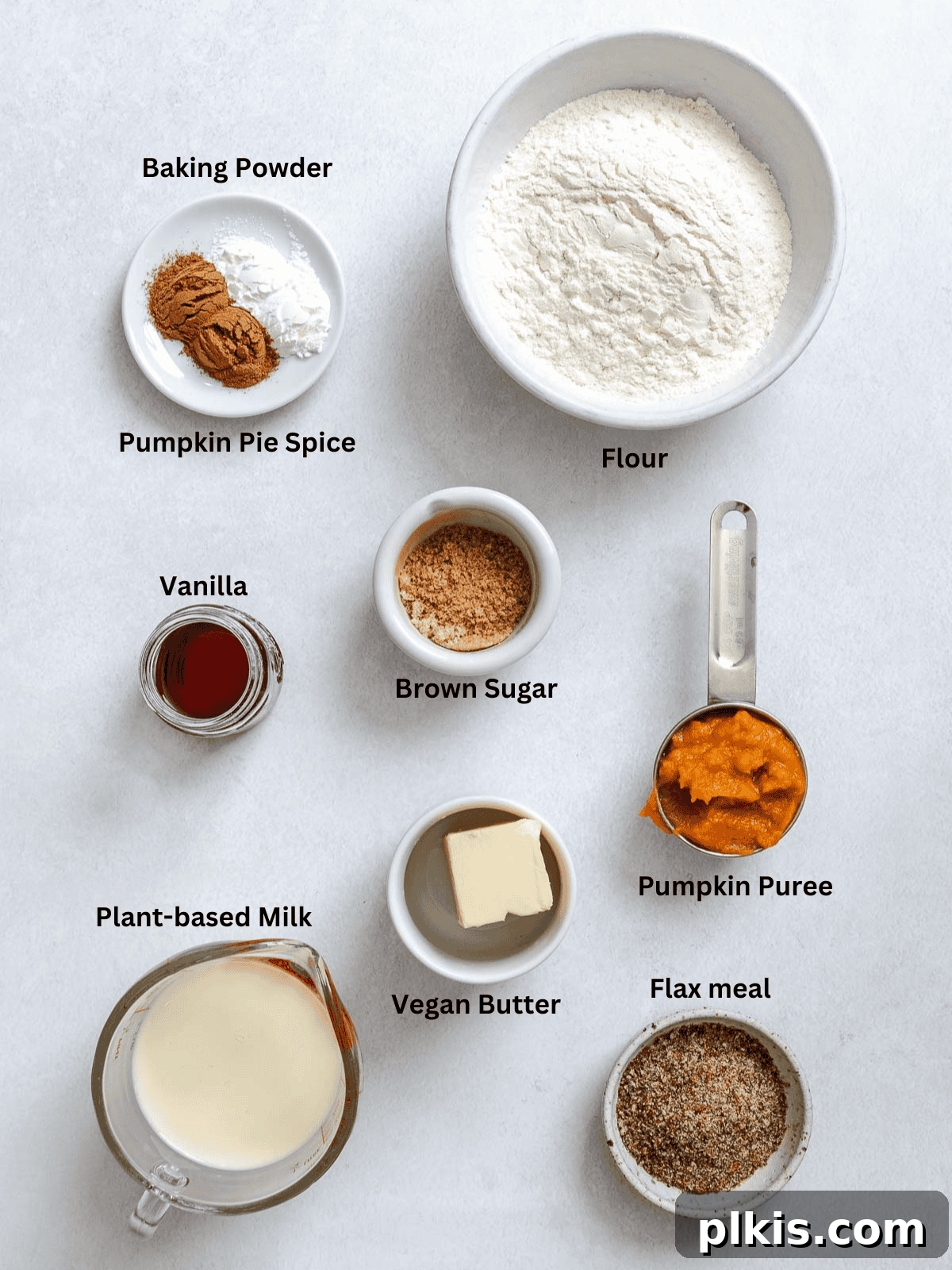 Plant-Based Pumpkin Patch Waffles 3 Ingredients for Vegan Pumpkin Waffles measured out on a white surface, including flour, pumpkin puree, plant milk, flax meal, and spices.
