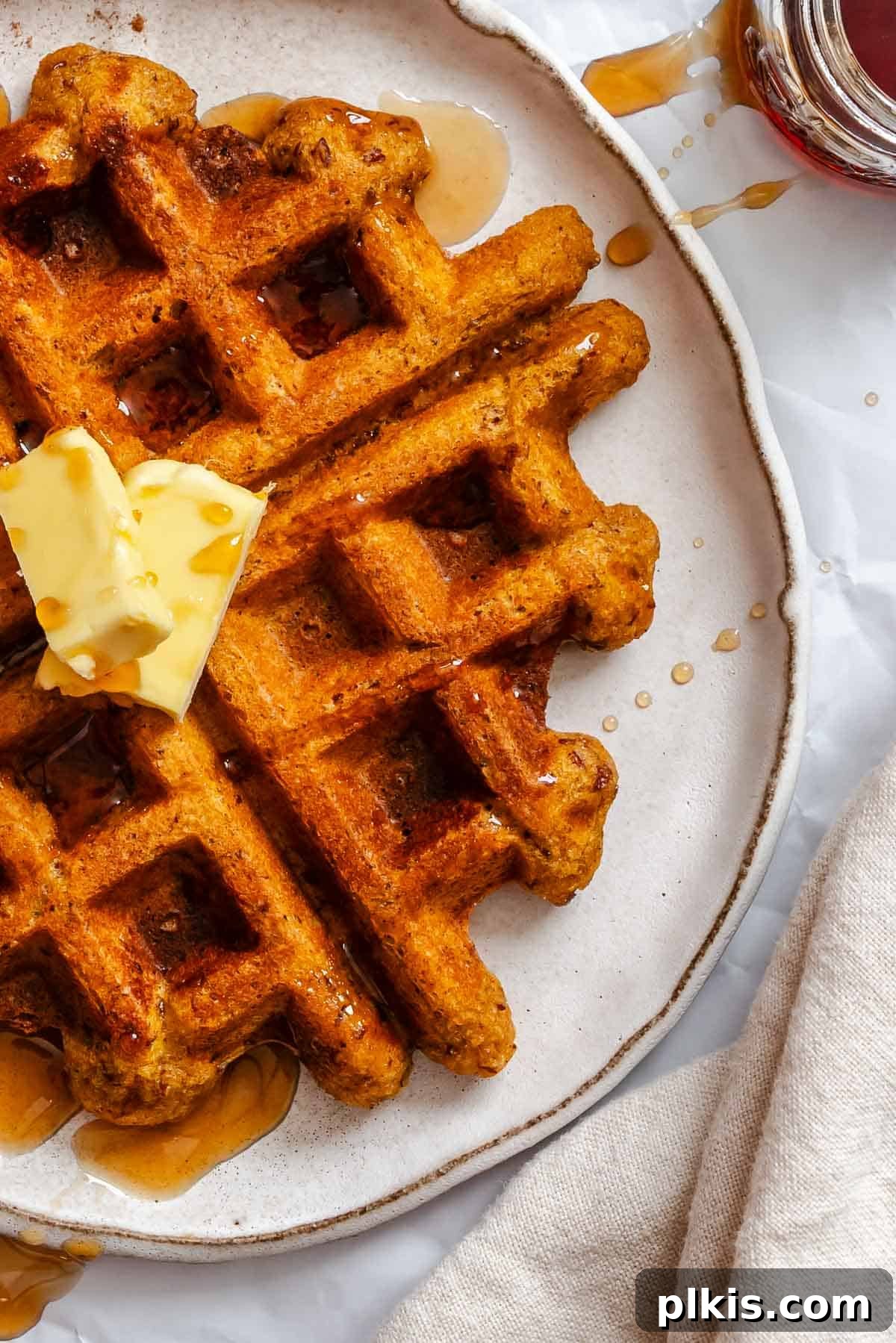 Plant-Based Pumpkin Patch Waffles 8 A stack of golden-brown Vegan Pumpkin Waffles, beautifully arranged on a white plate, ready to be served.