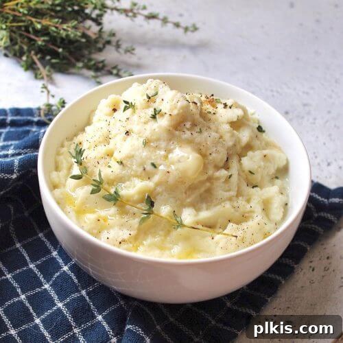 45 Mouthwatering Vegan Thanksgiving Recipes 16 A delightful bowl of finished mashed cauliflower, set against a blue towel and white background.