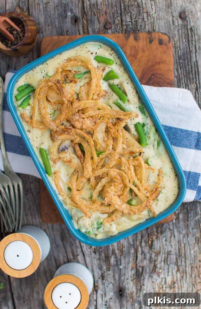 45 Mouthwatering Vegan Thanksgiving Recipes 20 A rustic image of a finished vegan green bean casserole in a blue dish against a dark gray wood background.