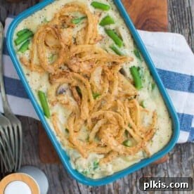 45 Mouthwatering Vegan Thanksgiving Recipes 21 A comforting green bean casserole, freshly baked in a blue tray against a dark gray surface.