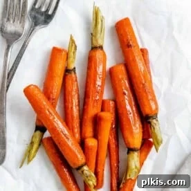45 Mouthwatering Vegan Thanksgiving Recipes 23 Completed glazed carrots, glistening and ready to serve, against a clean white surface.