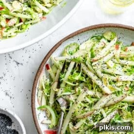 45 Mouthwatering Vegan Thanksgiving Recipes 25 Completed Shaved Brussel Sprout Slaw with Apples, served on a light surface.