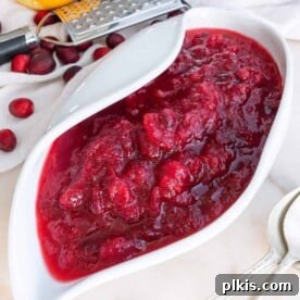 45 Mouthwatering Vegan Thanksgiving Recipes 43 Completed Homemade Cranberry Sauce, garnished with lemon zest and served in a white bowl against a white background.