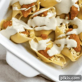 45 Mouthwatering Vegan Thanksgiving Recipes 61 Completed Pumpkin Stuffed Shells With Sage Cream in a white baking tray.
