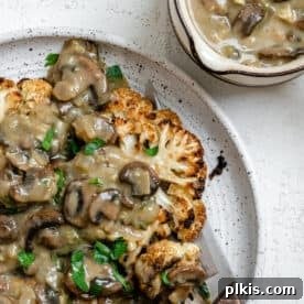 45 Mouthwatering Vegan Thanksgiving Recipes 63 Completed Cauliflower Steaks plated on a white plate against a white background.