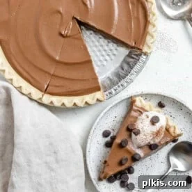 45 Mouthwatering Vegan Thanksgiving Recipes 65 Completed Chocolate Pumpkin Pie against a white surface with a slice missing and plated in the background.