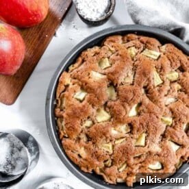 45 Mouthwatering Vegan Thanksgiving Recipes 70 Finished apple cake with two apples and measuring tools against a white background.