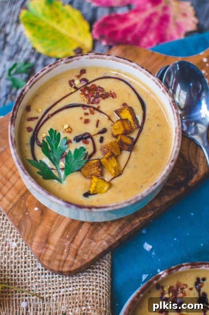 45 Mouthwatering Vegan Thanksgiving Recipes 6 A bowl of finished pumpkin soup, garnished and served on a rustic background with a cutting board and towels.