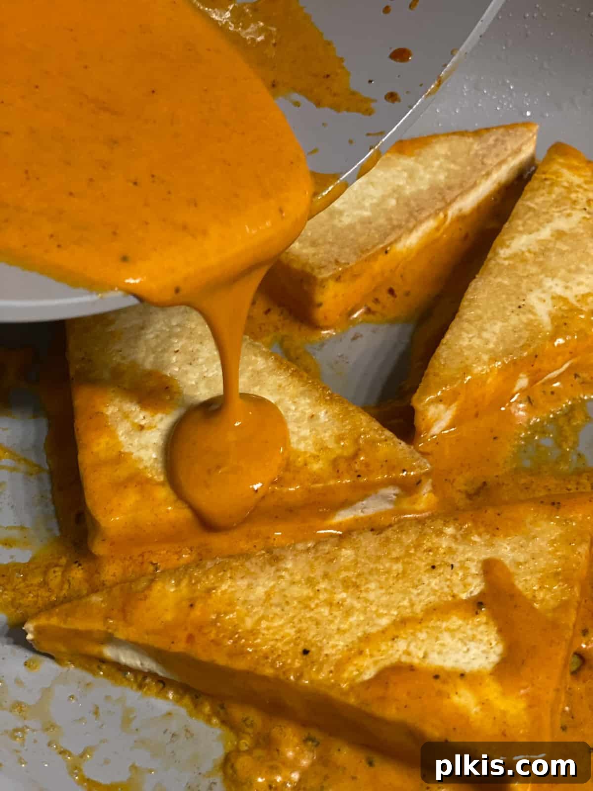 Buffalo Tofu Your Way: Easy Fried, Baked, or Air-Fried 11 Process shot of flipping the tofu wedges and adding the remaining buffalo sauce for even coating